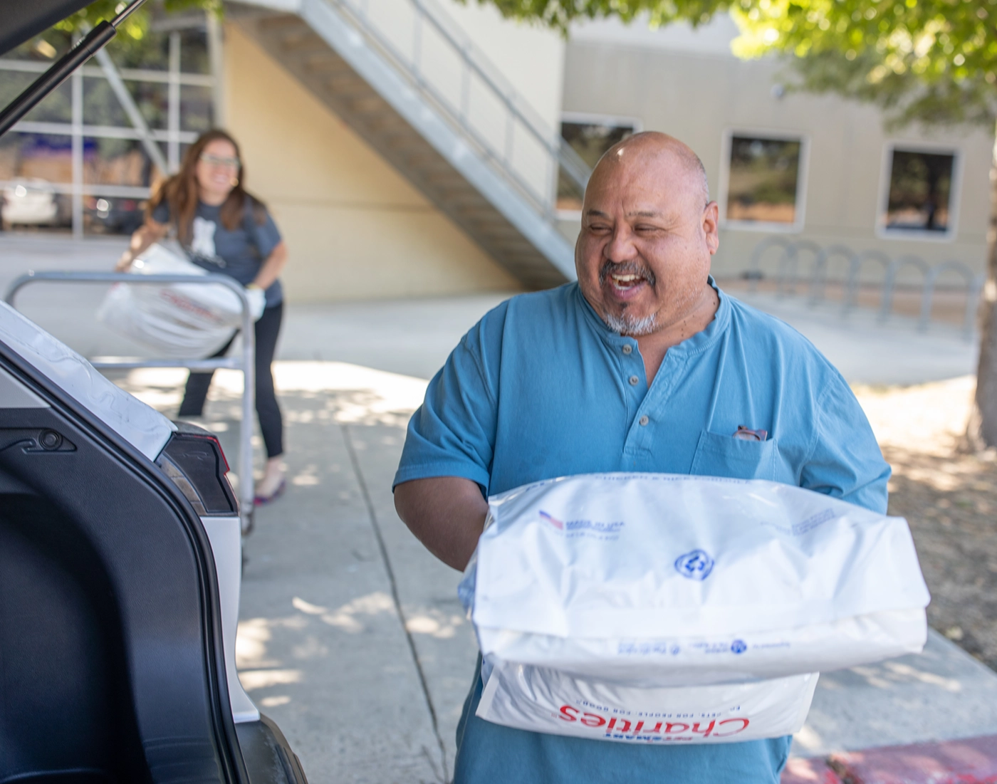 Man loading large bag of pet food into the back of a car.